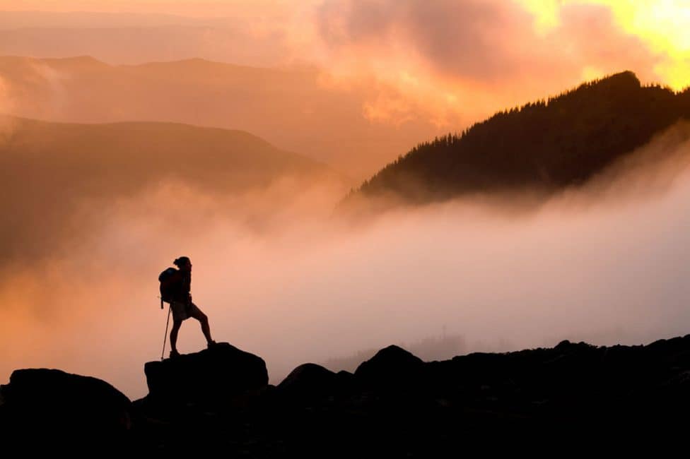 Scout silhouette at summit above the clouds